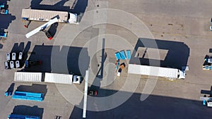 Trucks with semi-trailers stand on the parking lot of the logistics park with loading hub and wait for load and unload goods at