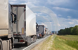 Trucks are stuck in traffic. A column of semi-trailers on the freeway. Concept of disruption in transportation logistics