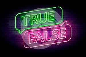 True and false neon sign with speech bubbles on a brick wall.