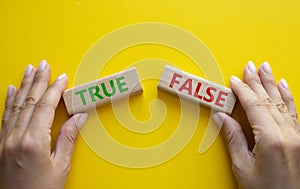 True or False symbol. Concept word True or False on wooden blocks. Businessman hand. Beautiful yellow background. Business and