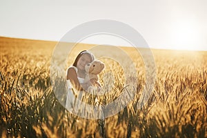 The true love of her childhood. a cute little girl playing with her teddybear in a cornfield.