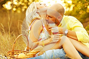 True romance concept. Weekend picnic. Portrait of a young loving couple in trendy casual clothes drinking red wine and kissing.