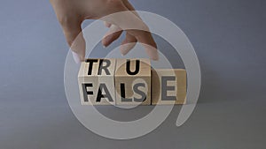 True vs False symbol. Businessman Hand turns cubes and changes word False to True. Beautiful grey background. Business and True vs
