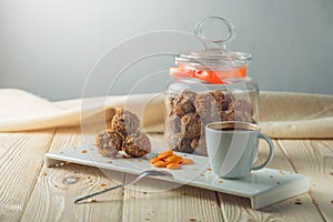 Truffle balls with orange chocolate on the saucer next to the jar of candy and a Cup of coffee.