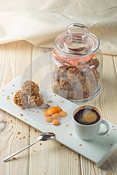 Truffle balls with orange chocolate on the saucer next to the jar of candy and a Cup of coffee.