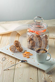 Truffle balls with orange chocolate on the saucer next to the jar of candy and a Cup of coffee.