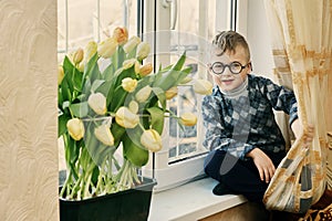 A truly adorable boy home with tulips .