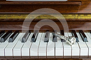 Trumpet mouthpiece upon the piano keys, close up