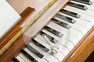 Trumpet mouthpiece upon the piano keys, close up