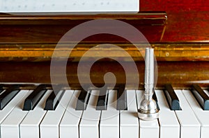 Trumpet mouthpiece upon the piano keys, close up