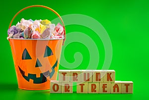 A Trunk or Treat SIgn and a Bucket FIlled with Candy