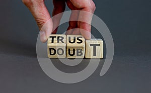 Trust or doubt symbol. Businessman flips wooden cubes and changes the word doubt to trust. Beautiful grey background, copy space.