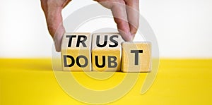 Trust or doubt symbol. Businessman turns wooden cubes and changes the word doubt to trust. Beautiful yellow table, white