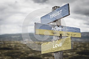 trust hope love text quote on wooden signpost outdoors, written on the ukranianflags