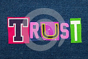 TRUST text word collage in brightly colored fabric on blue denim, confidence and fidelity photo