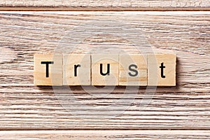 TRUST word written on wood block. TRUST text on table, concept