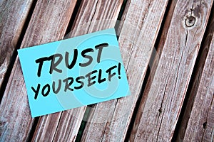 Trust yourself. Motivational or inspirational quote handwritten on paper on a wooden table.