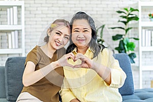 In truth, a family is what you make it. Shot of happy smiling asian senior mother and daughter making a heart sign with their