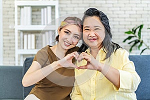In truth, a family is what you make it. Shot of happy smiling asian senior mother and daughter making a heart sign with their