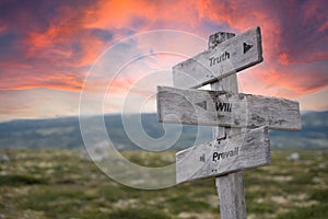 Truth will prevail text engraved in wooden signpost outdoors in nature during sunset and pink