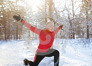 TRX suspension training concept. Athletic senior man working out with sports equipment on snowy winter day at park