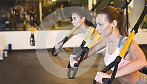 TRX training. Girls training triceps with fitness straps