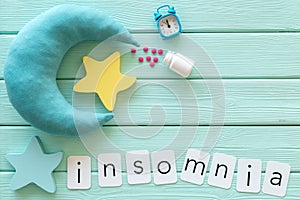Insomnia concept with moon, stars, alarm clock and pills on mint green wooden background top view