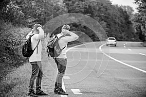 Try to stop some car. Travel and transport concept. Twins men at edge of road nature background. Reason people pick up