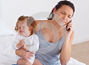 Trying to balance it all - Motherhood. A mother trying to have a phone conversation while her baby is crying in the