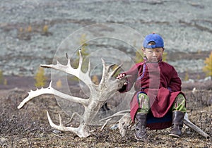 Tsaatan boy, dressed in a traditional deel with a reindeer horn