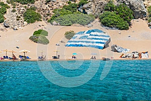 Tsambika beach with golden sand with big Greek flag painted on r