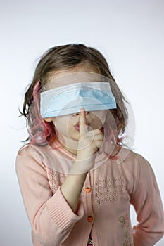 Tsss! little kid girl with mask on face showing silence gesture