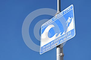 Tsunami hazard zone warning sign on blue sky