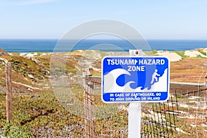 Tsunami warning sign along a through coastal sand dunes