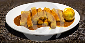 Tteok bokki on white plate on leathed board photo