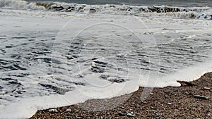 Tthe incoming sea foam rushing up the beach in south east Cornwall