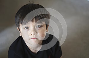 TTop view head shot kid looking up with copy space, Candid young boy looking at camera with curiouse face, Child sitting on floor