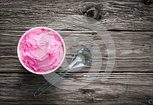 Tub of berry ice cream on a rustic wood table