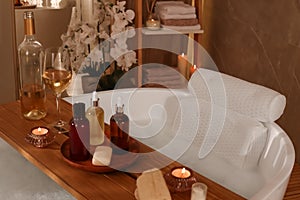 Tub with soft bath pillow, toiletries and wine indoors