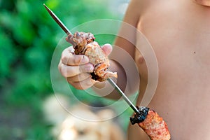 Tubby boy with pleasure eats a shish kebab. Camping. Healthy nutrition and diet.