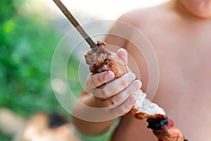 Tubby boy with pleasure eats a shish kebab. Camping. Healthy nutrition and diet.