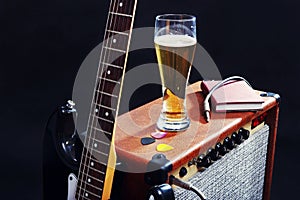 Tube combo for guitar with black guitar, glass of beer and notepad on black background