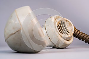 Tube from an white old landline phone. Macro shot of a dirty plastic telephone receiver with holes. Removed phone