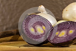 Tubers of onions Allium cepa cut in halves on wooden board