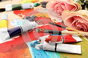 Tubes of colorful oil paints, flowers and brushes on canvas