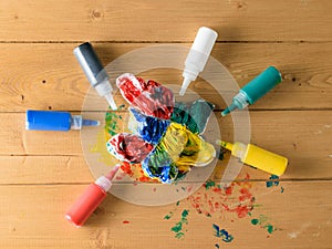 Tubes of fabric paint and a painted t-shirt on a wooden rustic table.