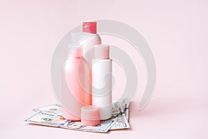 Tubes with hygiene products on dollar bills against pink background photo