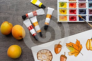 Tubes of paint on a wooden table, palette, autumn watercolor drawing, bright composition