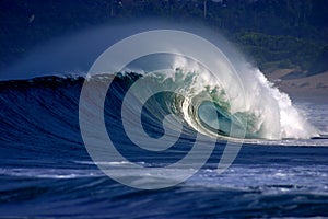 Tubular surfing wave breaking onto tropical beach