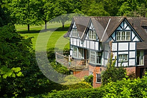 Tudor house surrounded by trees and shrubs.